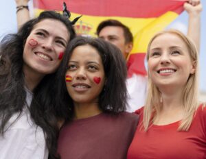Adolescentes rumanos sonrientes con la bandera de España tras obtener la nacionalidad española para residentes rumanos menores de 14 años